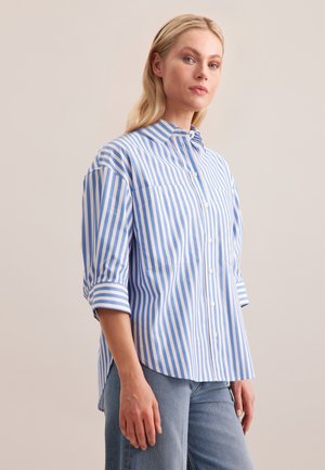 Chemise à rayures bleues et blanches avec un col, des manches retroussables et deux poches poitrine. Fabriquée dans un tissu à la texture lisse.