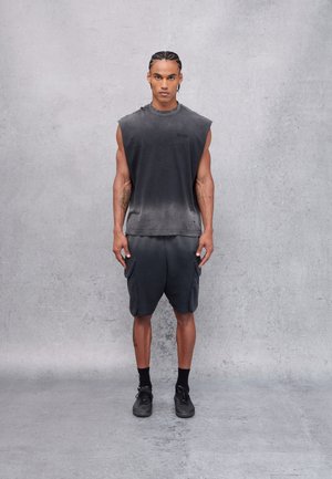 Camiseta sin mangas negra con un diseño en degradado, combinada con pantalones cortos cargo oscuros. Ambas prendas tienen una textura suave y un ajuste casual y relajado.