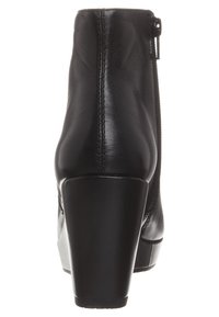 Černá kotníková obuv z hladké kůže s kulatou špičkou, vysokým blokovým podpatkem, zadním zipem a hladkou texturou. Má prošívání podél švů.