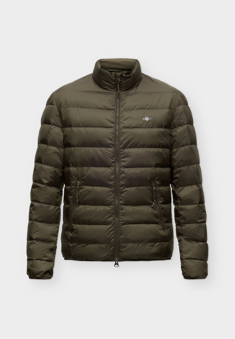 Olivgrüne gesteppte Steppjacke mit hohem Kragen, Frontreißverschluss, zwei seitlichen Reißverschlusstaschen und kleinem Brustlogo auf einfarbigem Hintergrund.