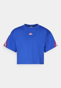 Blue cropped t-shirt made of cotton with a round neckline. Features red and white striped accents on the sleeves and a small logo on the chest.