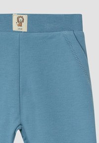 Lichtblauwe katoenen broek met een zachte textuur, voorzien van een vlakke tailleband, twee voorzakken en een gestikte label met een leeuwontwerp.