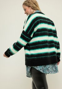 Gestreifter schwarzer und mintgrüner Strickcardigan mit lockerer Passform und weicher Textur. Trägt man über einem im Paisleymuster gehaltenen Hemd.
