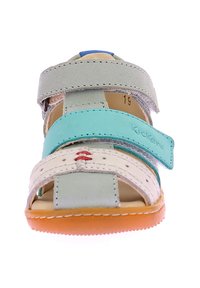 Sandalia multicolor con una parte superior verde claro, acentos en azul y blanco, correas de velcro y una suela de goma texturizada color naranja.