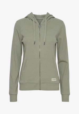 Felpa con zip di un verde oliva chiaro, caratterizzata da una texture a coste, cappuccio regolabile con coulisse, due tasche frontali e una piccola etichetta con logo.