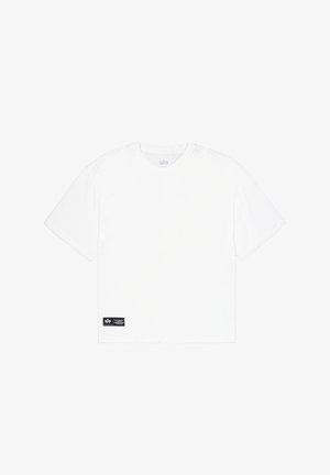T-shirt en coton blanc à manches courtes, col rond, avec une étiquette de marque noire en bas à gauche. Design simple, sans motifs ni graphiques.