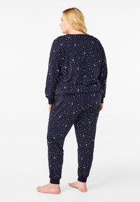 Navy pajama set featuring scattered white star and moon patterns. Made of soft fabric, with long sleeves and elasticated cuffs and waistband.