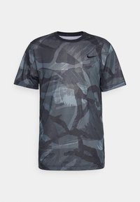 Camiseta deportiva de manga corta en gris oscuro con un patrón de camuflaje abstracto. Fabricada en tejido ligero, con cuello redondo y un pequeño logo en el pecho.