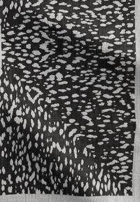 Tissu noir et gris à motifs avec des formes et textures abstraites, présentant une finition lisse et une bordure d'une couleur gris clair.