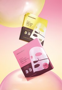 Dwie intensywnie kolorowe opakowania na maski hydrożelowe, jedno żółte, a drugie różowe, umieszczone na tle delikatnego gradientu.