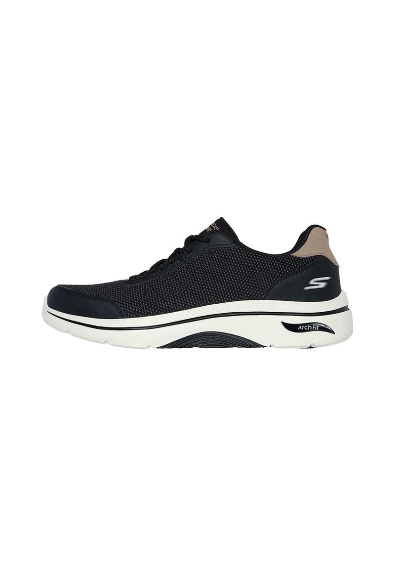 Zapatilla deportiva negra con una parte superior de malla texturizada, entresuela acolchada y suela de goma blanca. Presenta sutiles acentos en color marrón y un logotipo.