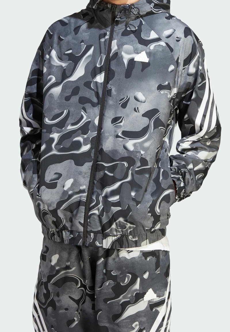 Black and gray camouflage windbreaker with a zip front, elastic cuffs, and waistband. Features white striped accents on sleeves.