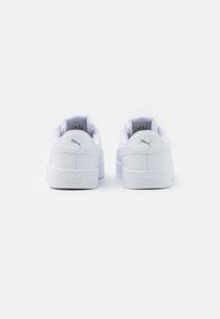 White sneakers with a smooth leather upper, padded collar, and a thick rubber sole. Features subtle branding on the heel and tongue.