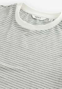 Stribet t-shirt i hvid og sort, lavet af bomuld, med en ribbet rund halsudskæring og vandrette striber i varierende tykkelse.