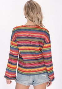 Camicetta a maniche lunghe multicolore con motivo geometrico in rosso, giallo, blu e verde. Realizzata in un tessuto testurizzato con una vestibilità ampia.
