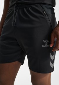 Schwarze Sportshorts aus einem glatten, leichten Material. Mit einem Kordelzugbund, einer seitlichen Reißverschlusstasche und reflektierenden Logoakzenten.