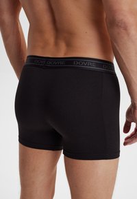 Sorte bomuldsboxershorts med en glat tekstur, der har en bred elastisk talje, hvor brandnavnet er trykt i en diskret grå farve.