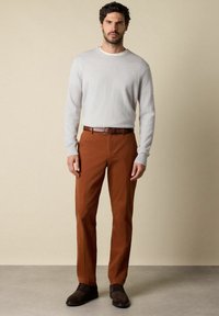 Světle šedý pletený svetr, hnědé kalhoty, hnědý kožený opasek a odpovídající boty. Oblečení má jednoduchý design s klasickým střihem.