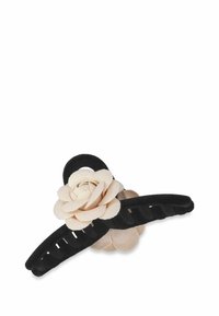 Svart hårklämma med en texturerad, böjd design som har ett beige konstblomsinslag. Klämman är tillverkad av plast och har ribbad detaljering.