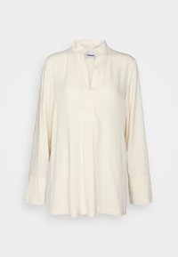 Blouse à manches longues couleur crème avec un petit col montant et un décolleté en V, présentée sur un fond clair uni.