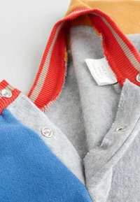 Grau, blau und gelb farblich blockiertes Hemd mit rohem, geripptem Kragen, silbernen Knöpfen und einem weichen Innenfutter. Etikett innen sichtbar.