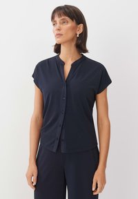 Navy button-up top with short sleeves, made of soft fabric. Features a mandarin collar and a smooth texture, designed for a relaxed fit.
