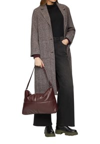 Bruin en witte houndstooth overjas, zwarte turtleneck, zwarte wijde jeans, bordeauxleren schoudertas en zwarte platformlaarzen.