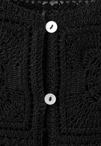 Cárdigan negro de punto con patrones intrincados, tela texturizada y dos botones blancos en la parte delantera para el cierre.