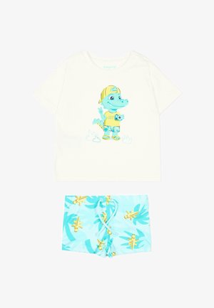 Completo per bambina con maglietta bianca decorata con un coccodrillo dei cartoni animati con cappello e pantaloncini, abbinata a pantaloncini blu con fantasie di coccodrilli gialli e foglie.