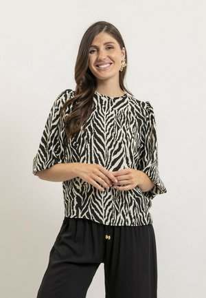 Haut rayé noir et blanc avec des manches courtes, un col rond et une coupe décontractée, associé à un pantalon noir avec des accents dorés.