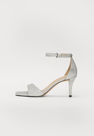 Silberne Glitzer-High-Heel-Sandaletten mit einem Knöchelriemen, offenen Zehen und einem schmalen Absatz. Glatte Textur und minimalistisches Design.