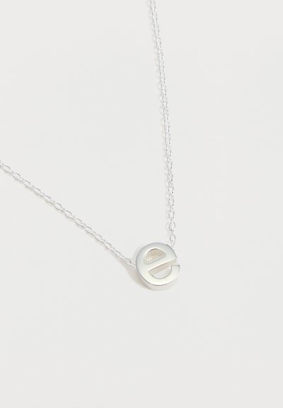 Collier chaîne en argent avec un pendentif circulaire représentant une lettre minuscule "e" sur un fond blanc uni.