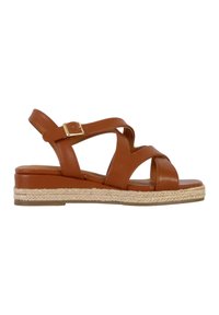 Sandale en cuir marron avec des brides entrecroisées. Dotée d'un talon compensé bas avec une texture en corde et un accent de boucle dorée.