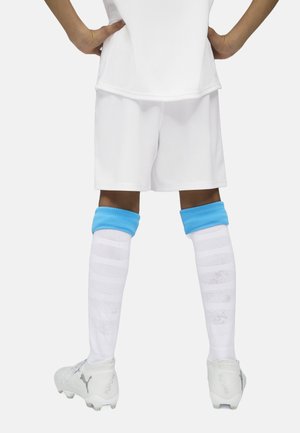 Shorts de football blancs associés à des chaussettes montantes bleu et blanches. Les chaussettes présentent un motif texturé. Les crampons sont blancs avec des accents argentés.