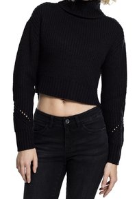 Schwarzer, kurz geschnittener Rollkragenpullover mit gerippter Textur und offen gestrickten Details an den Ärmeln, kombiniert mit schwarzen Jeans.