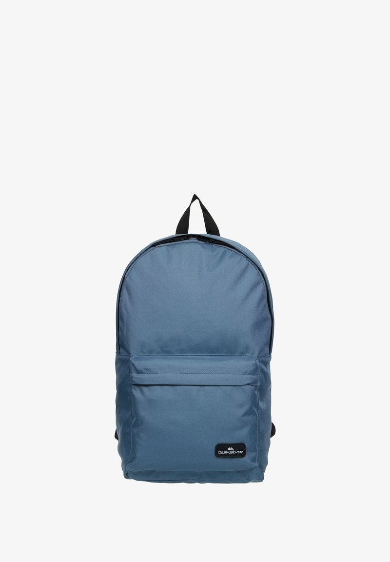 Sac à dos en tissu bleu avec un sommet arrondi, une poche avant, des bretelles ajustables et une étiquette de logo. Texture lisse avec un design minimaliste.