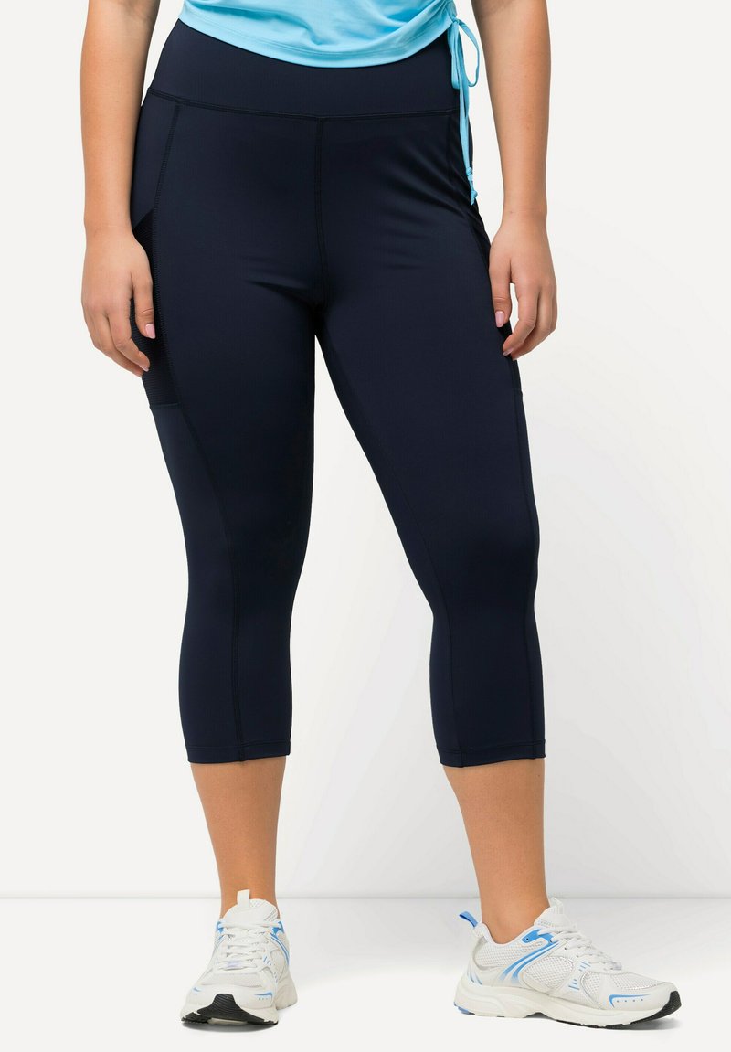 Leggings capri della marina realizzati in tessuto elasticizzato con tasche laterali. Presentano una vita liscia e dettagli di cucitura a contrasto.