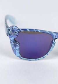 Lunettes de soleil bleues avec des verres teintés en violet, dotées d'une monture à motifs et de personnages de dessin animé sur les branches. Fabriquées en plastique.