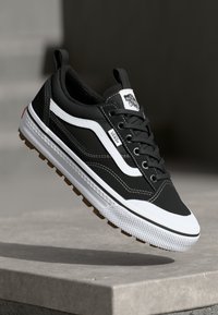 Black and white sneaker featuring a leather and textile upper, rubber outsole, lacing system, and a logo patch on the tongue.