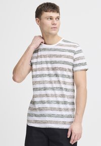 Striped t-shirt in white, green, and brown. Short sleeves, round neck, soft texture. Horizontal wavy stripes create a casual design.