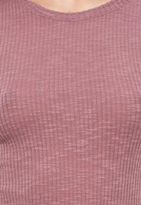 Ριμπ πλεκτό τοπ σε απαλό μωβ χρώμα με στρογγυλή λαιμόκοψη. Το ύφασμα έχει διακριτική υφή και αγκαλιάζει το σώμα για μια κομψή εμφάνιση.