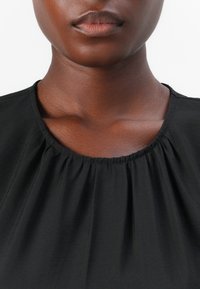 Mustikasade blouse, millel on ümar kaelus, rühmas kangaga krae ja pehme tekstuur. Taust on ühtlane valge.