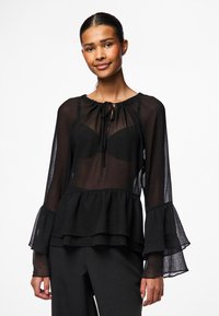 Black sheer blouse with a round neckline, drawstring detail, and flared long sleeves. Layered ruffle hem adds texture to the design.