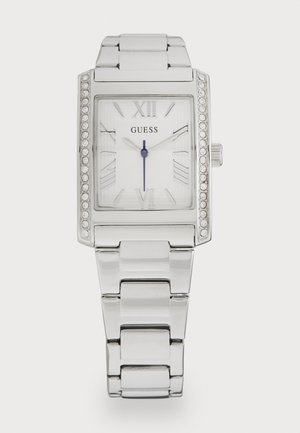 Montre rectangulaire argentée avec un cadran blanc, des chiffres romains, un bracelet en maillon argenté et des accents en cristal autour de la lunette.