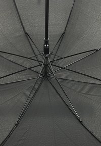 Schwarzer Regenschirm von unten betrachtet, der eine gerippte Struktur mit einem zentralen Rohr, metallischen Speichen und einer strukturierten Oberflächenspannung zeigt.