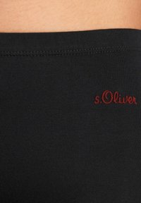 Tessuto elasticizzato nero con texture a coste, caratterizzato da un logo "s.Oliver" ricamato in rosso sulla vita. Vista ravvicinata di un design senza cuciture.