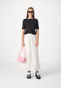 Black short-sleeve top, white maxi skirt with drawstring, black platform sandals, white socks, and a small pink handbag.