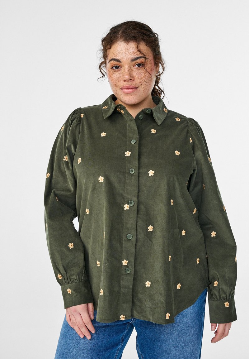 Grünes Cordhemd mit durchgehender Knopfleiste, langen Ärmeln und beige floral bestickten Details sowie Raffung an den Schultern.