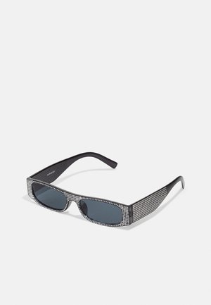 Crne sunčane naočale s sivim staklima, sa uzorkom rešetke sitnih metalnih štrasnih kamenčića duž okvira. Glatka površina, uglasti dizajn.