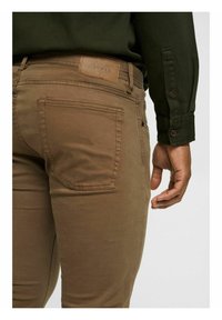 Bruine katoenen broeken met een getailleerd ontwerp, voorzien van een zichtbare achterzak en een leren label met "Esprit" op de taille.